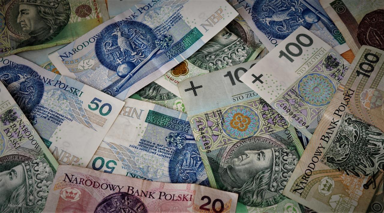Stos banknotów polskich złotych o różnych nominałach (20, 50, 100), ułożonych warstwami, z widocznymi wizerunkami królów i godła Polski, z różnym oświetleniem i kątami nachylenia.