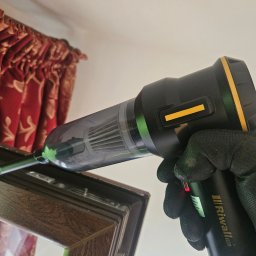 Serwis Domowy Valdi , Waldemar Michalski - Czyszczenie ramy okiennej odkurzaczem ręcznym Riwall Pro. Drobne zabrudzenia w narożnikach usuwane przez osobę w rękawicy roboczej. Widoczne zasłony w tle.