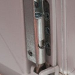 Serwis Domowy Valdi , Waldemar Michalski - Regulacja zawiasu okiennego kluczem imbusowym. Widoczny mechanizm okna, śruby mocujące i dłoń montera. Detal naprawy okna PCV.