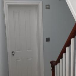 Drzwi drewniane białe z futryną stałą z opaskami. 