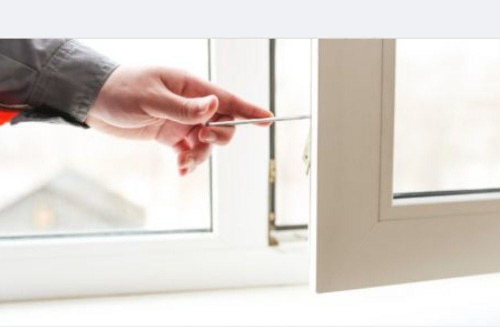 Regulacja okna w Toruniu: dłoń przy użyciu narzędzia reguluje białe okno z widocznym mechanizmem.