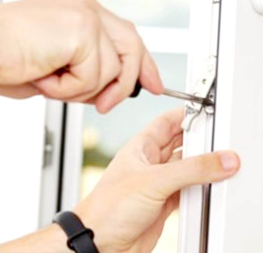 Regulacja okucia okiennego za pomocą śrubokręta, widoczne dłonie i fragment ramy okiennej z mechanizmem blokującym.