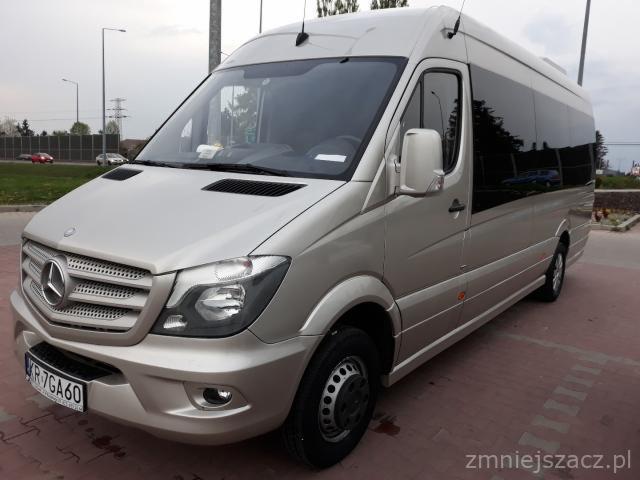 Złoty bus Mercedes-Benz Sprinter z przyciemnionymi szybami, zaparkowany na kostce brukowej, widok z przodu i boku.