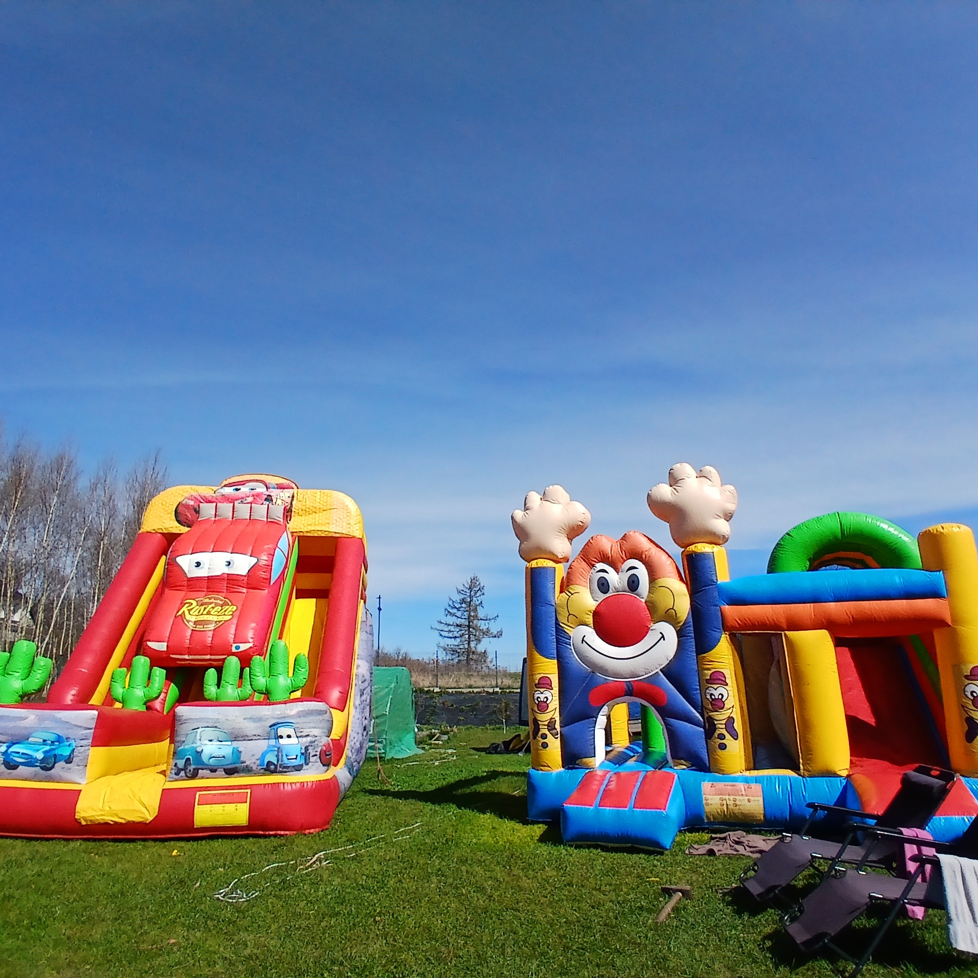 Kolorowe dmuchańce z motywami bajkowymi na trawie w Bolesławcu, pod błękitnym niebem. Atrakcje dla dzieci na imprezę plenerową.