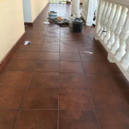 Brązowa terakota na zewnątrz, widoczne ślady po malowaniu, wiadro, kuweta i pędzle malarskie, biała balustrada w tle.