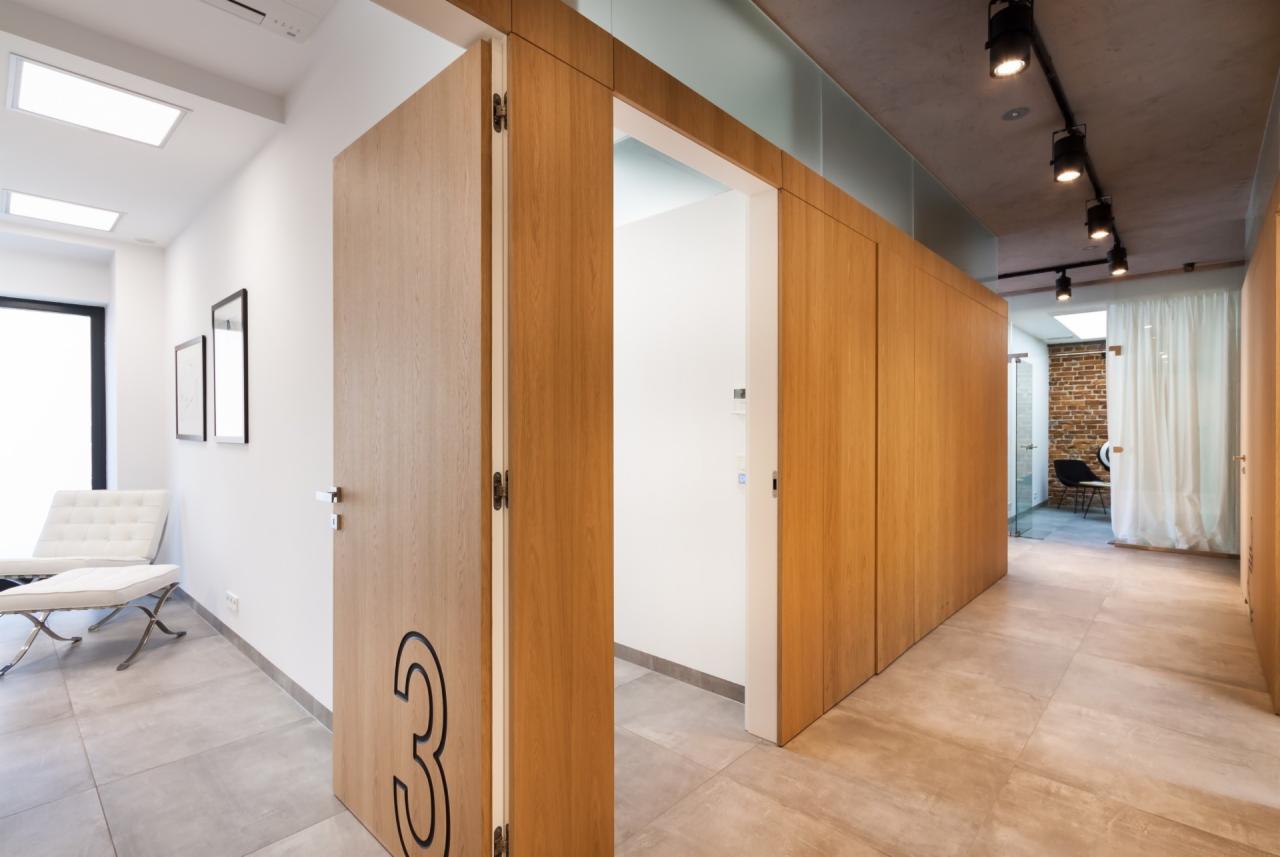 Wnętrze gabinetu z drewnianymi drzwiami oznaczonymi numerem 3, widoczne fotele i oświetlenie sufitowe