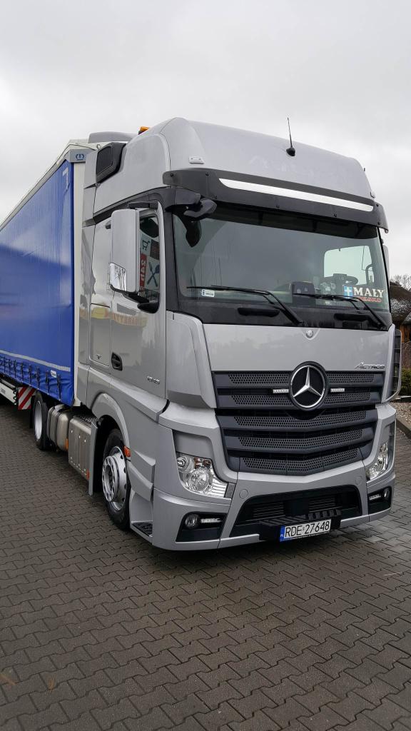 Srebrny ciągnik siodłowy Mercedes-Benz Actros z naczepą, zaparkowany na kostce brukowej w Besku, widok z przodu, tablica rejestracyjna RDE 27648, naklejka 'MAŁY' na szybie.