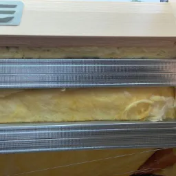 Montaż izolacji z wełny mineralnej w profilach metalowych pod płytę karton gips na poddaszu.