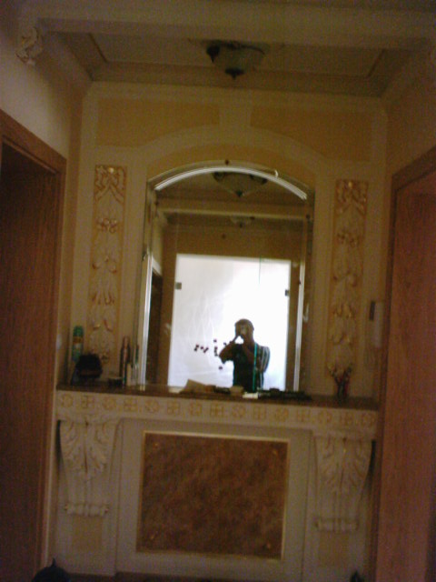 Wykończona wnęka z lustrem w łazience, dekoracyjne sztukaterie, odbicie osoby robiącej zdjęcie.