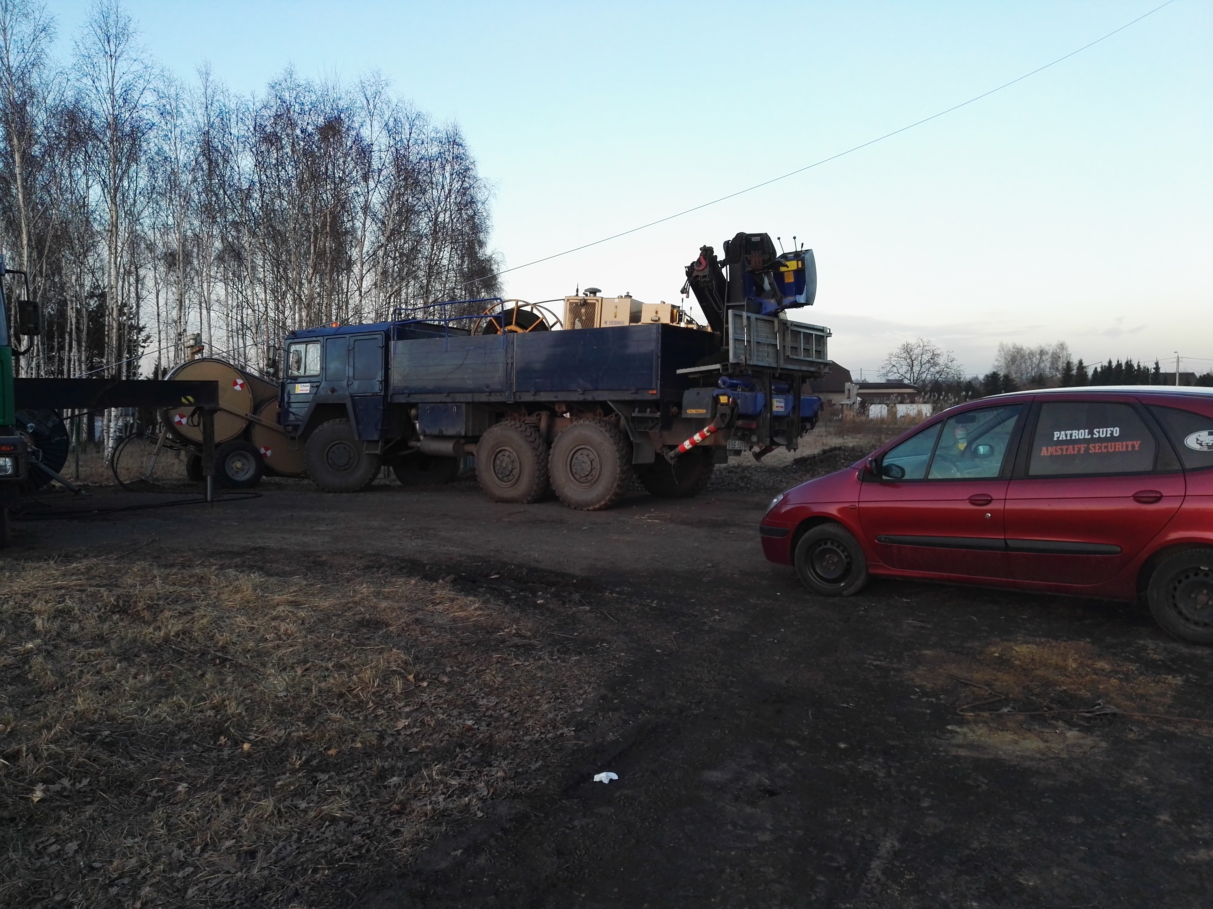 Ciężki sprzęt w Wodzisławiu Śląskim: samochód patrolowy Amstaff Security zaparkowany obok specjalistycznego pojazdu z dźwigiem.