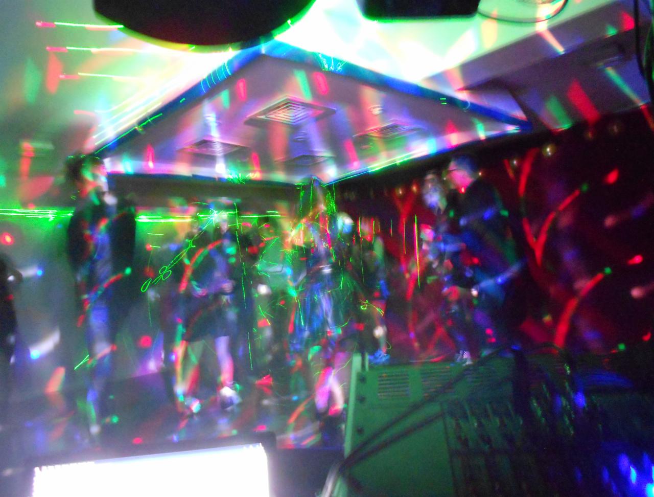 Zespół muzyczny grający na scenie oświetlonej kolorowymi światłami podczas imprezy.