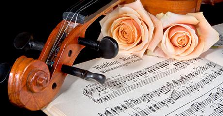 Skrzypce z partyturą 'Wedding March' i dwoma brzoskwiniowymi różami na czarnym tle.