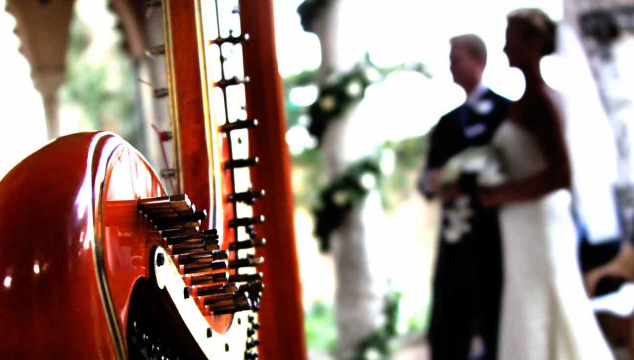 Bliski plan czerwonej harfy koncertowej z parą młodą w tle podczas ceremonii ślubnej na zewnątrz.