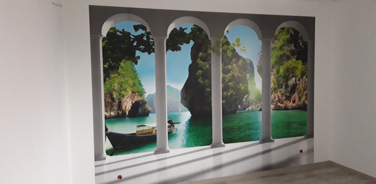 Fototapeta z motywem tropikalnego krajobrazu z łodzią i formacjami skalnymi, imitująca widok z balkonu z kolumnami, naklejona na ścianie w jasnym pomieszczeniu.
