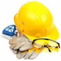 Żółty kask budowlany, rękawice robocze, okulary ochronne i maska przeciwpyłowa ułożone na białym tle.