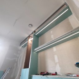 MED-BUD - Sufit podwieszany z oświetleniem LED w trakcie montażu z płyt karton-gips w Tarnowskich Górach. Widoczne narzędzia i elementy konstrukcyjne.