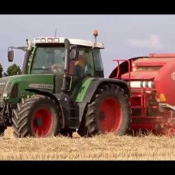 Zielony traktor Fendt 716 z czerwoną prasą zwijającą na polu ze słomą, widok z boku, w tle drzewa i błękitne niebo.