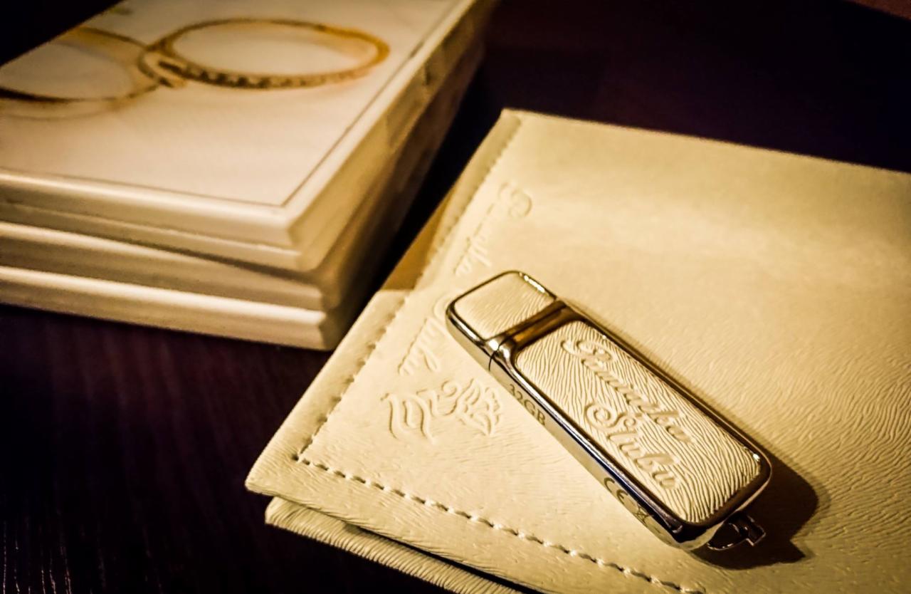 Elegancki pendrive 32GB z grawerem na kremowym etui, obok pudełka z motywem biżuterii, leżące na ciemnym blacie.