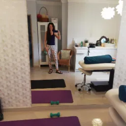 Odbicie w lustrze kobiety robiącej selfie w pomieszczeniu z matami do ćwiczeń i sprzętem do masażu w Sopocie.