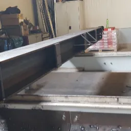 Element konstrukcji stalowej, spawany profil zamknięty z płytą czołową z otworami, widoczne ślady spawania i otoczenie warsztatowe.