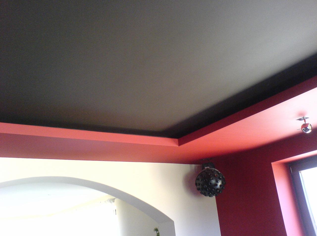 Dwupoziomowy sufit z czarną wnęką i czerwoną ramą, widoczna lampa dekoracyjna w kształcie kuli z otworami.