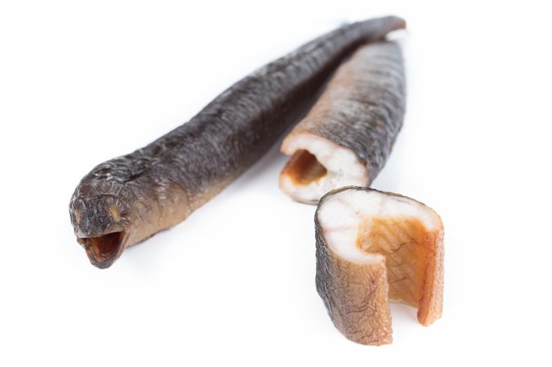 Wędzony węgorz w całości i przekrojony na białym tle.