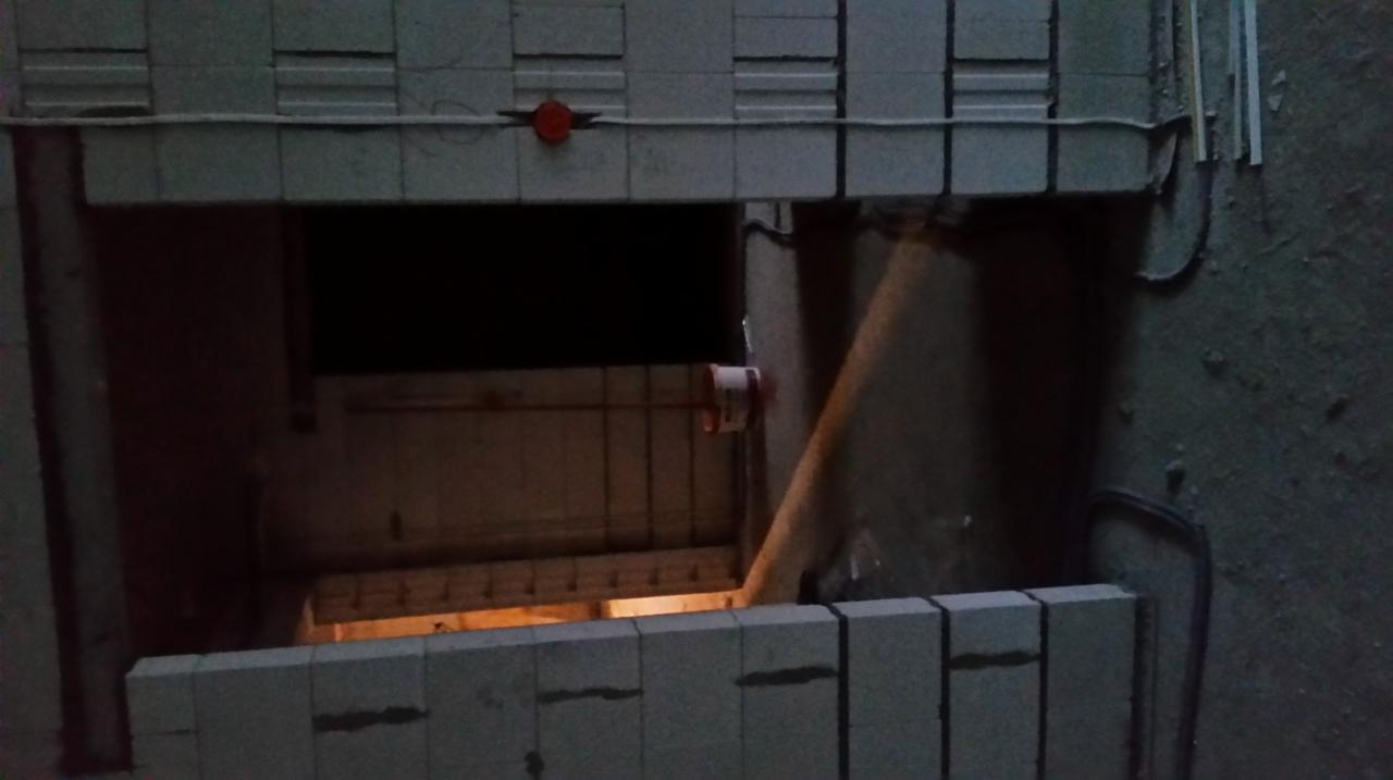Niedokończona konstrukcja z szarych bloczków, widoczne okablowanie elektryczne i elementy instalacji wewnątrz otworu.