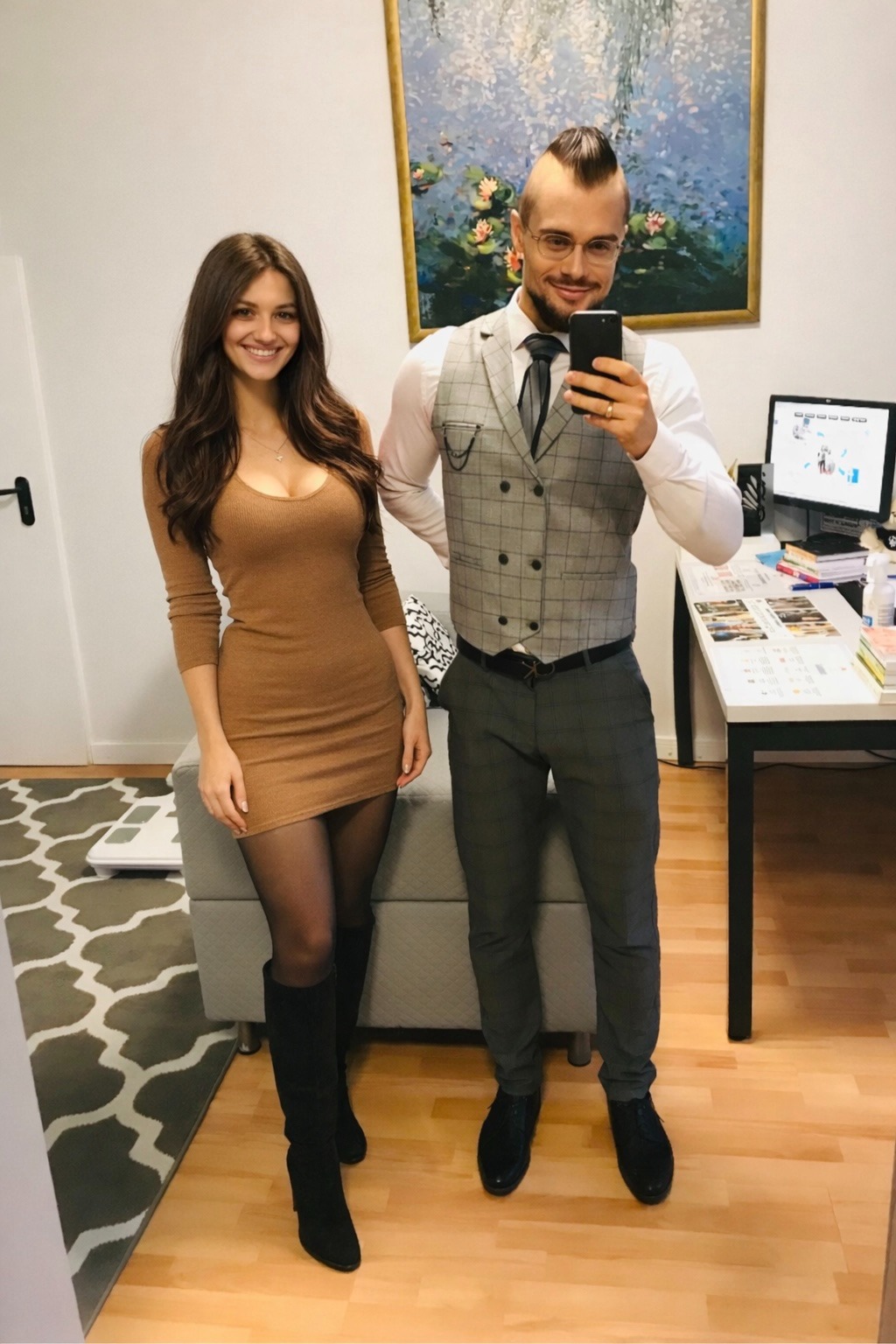 Dietetyk w eleganckiej kamizelce robi selfie z uśmiechniętą klientką w dopasowanej sukience na tle gabinetu z obrazem i wagą.