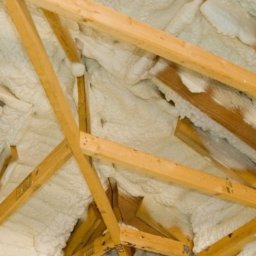 SCANDIPUR SPÓŁKA Z OGRANICZONĄ ODPOWIEDZIALNOŚCIĄ - Ocieplenie poddasza pianką PUR, widoczne drewniane krokwie i nierównomierna struktura piany.