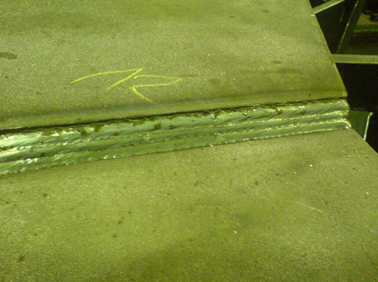 Spoina łącząca dwie metalowe płyty, widoczna żółta strzałka narysowana na jednej z płyt wskazująca kierunek.