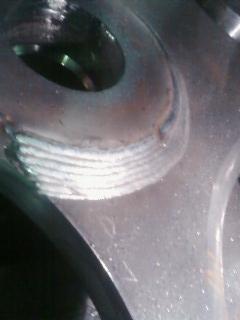 Szczegółowe zbliżenie na spoinę wykonaną metodą spawania TIG na metalowej powierzchni, widoczne regularne ślady po spawaniu, brak obróbki wykończeniowej.