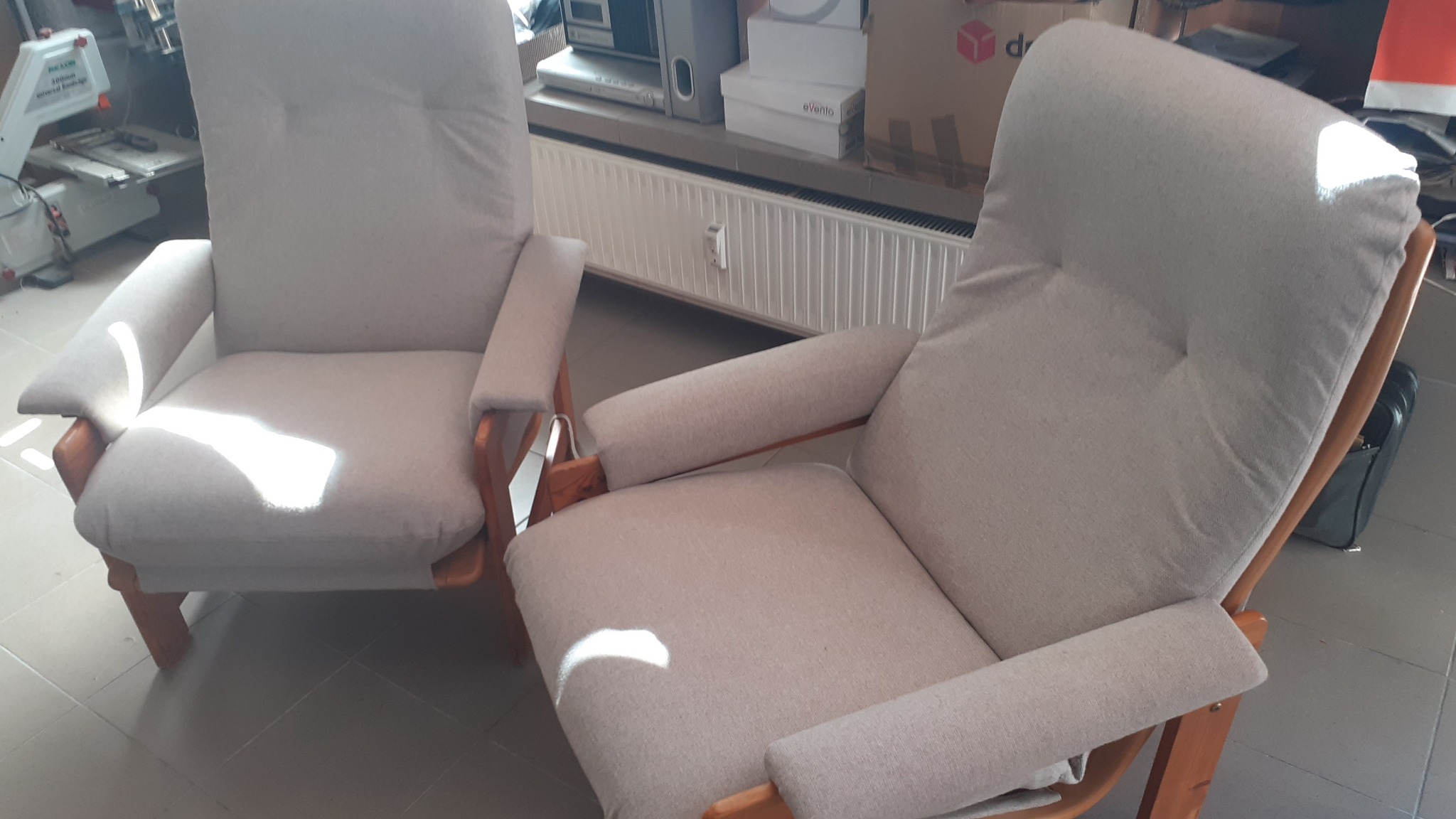 Dwa beżowe fotele tapicerowane z drewnianymi podłokietnikami, wykonane na wymiar w Kielcach, widoczne w warsztacie stolarskim.