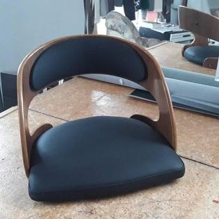 Krzesło z tapicerowanym siedziskiem i oparciem z giętego drewna w trakcie produkcji, widoczne elementy warsztatu w tle.