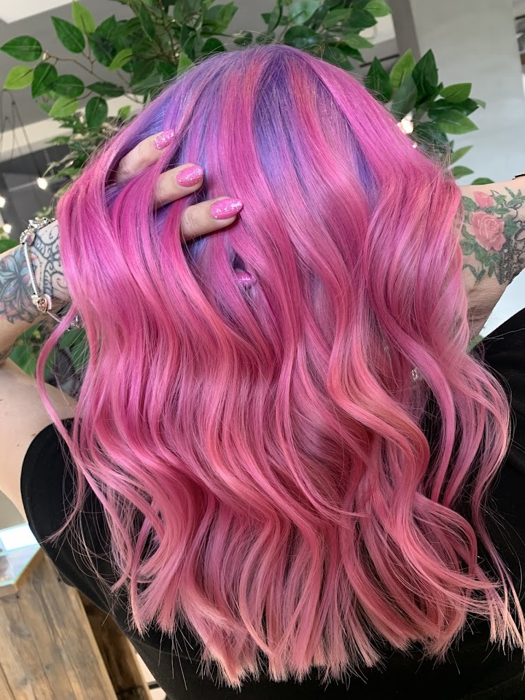 Włosy po koloryzacji w odcieniach różu i fioletu, widoczne delikatne fale i tatuaż na ramieniu