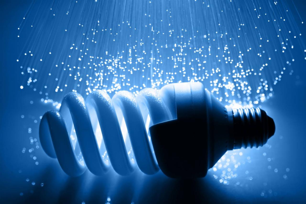 Energooszczędna żarówka spiralna w chłodnym, niebieskim oświetleniu, otoczona światłowodami tworzącymi efekt rozgwieżdżonego nieba.