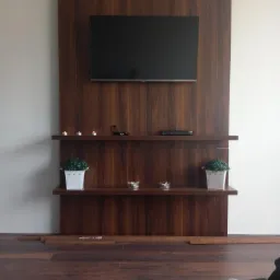 Drewniana zabudowa ściany z telewizorem, dwiema półkami, dekoracjami i oświetleniem punktowym, dopasowana kolorystycznie do podłogi.