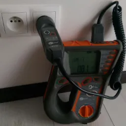 Miernik Sonel MPI-505 z podłączoną sondą w gniazdku elektrycznym, wyświetlający wartość pomiaru na ekranie.