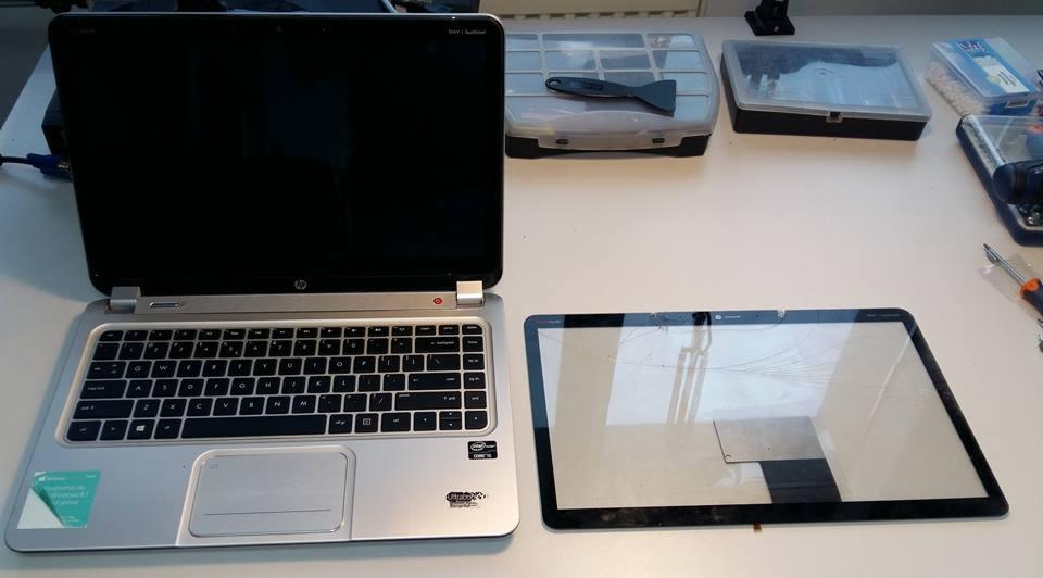 Uszkodzony ekran laptopa obok sprawnego urządzenia HP w Bielsku-Białej, na białym stole widoczne narzędzia i pudełka z częściami.