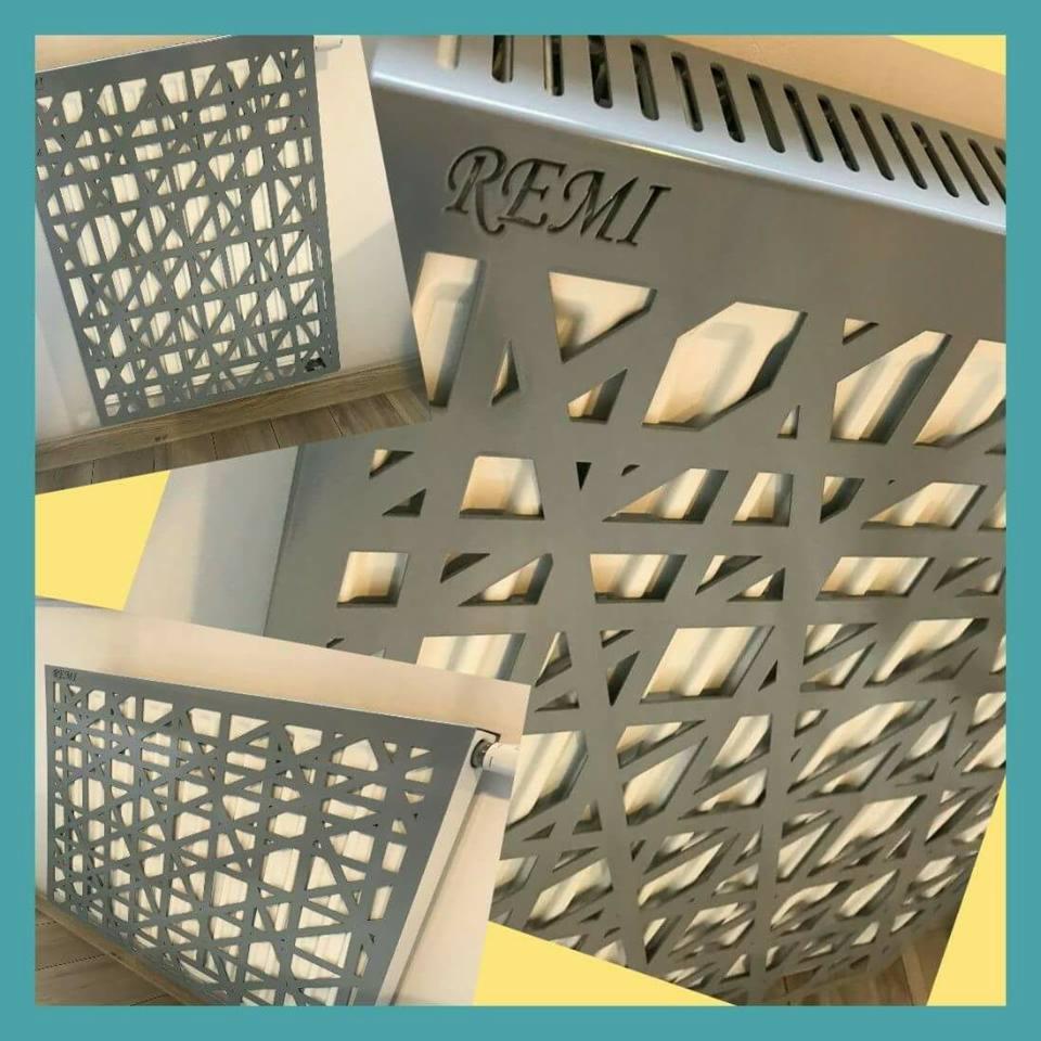Szara, metalowa osłona grzejnika z wycinanym laserowo wzorem geometrycznym i napisem 'REMI', prezentowana w trzech różnych ujęciach.