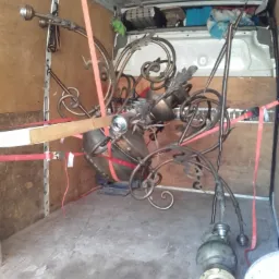 Antyczny żyrandol z metaloplastyki zabezpieczony czerwonymi pasami wewnątrz furgonetki podczas transportu.