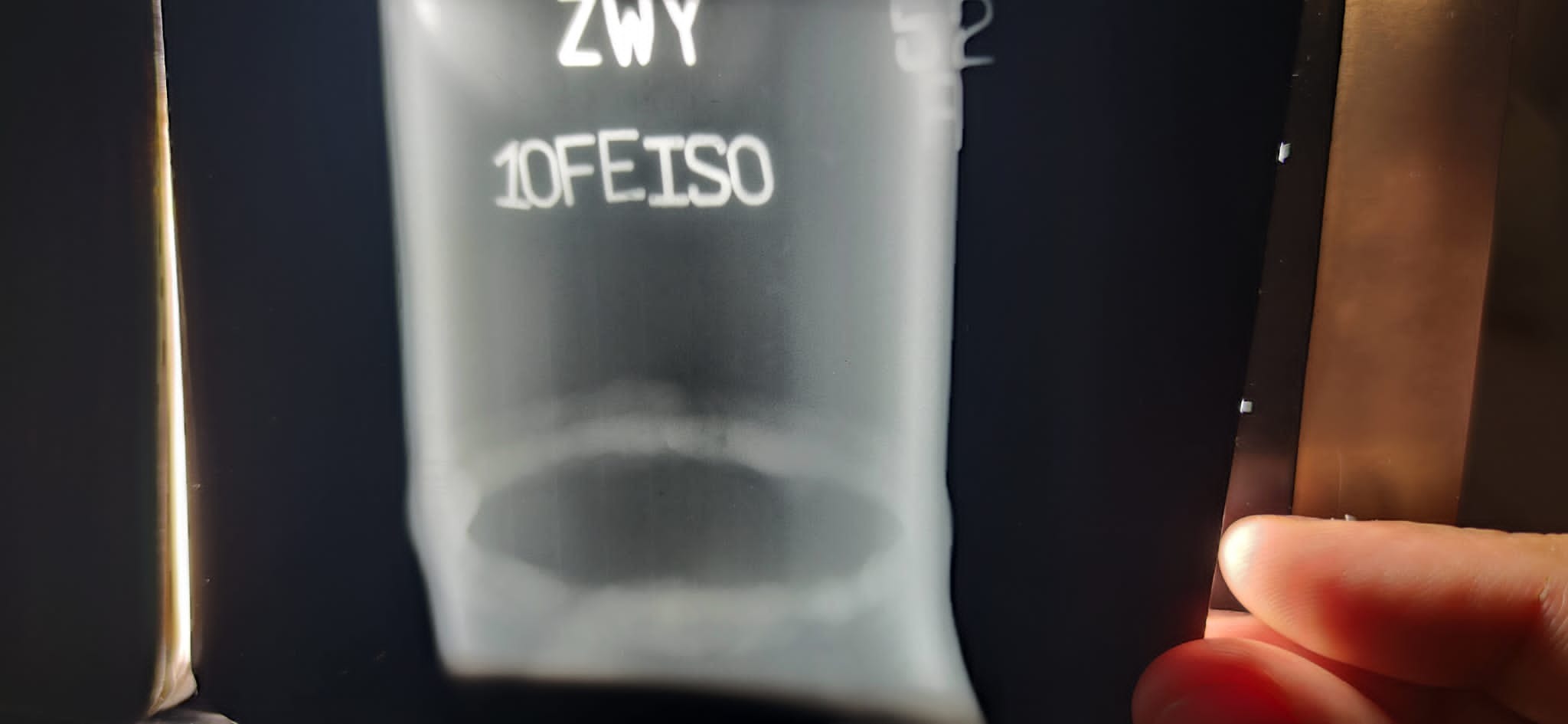 Rentgenowski obraz spoiny z widocznymi oznaczeniami ZWY i 10FEISO, trzymany w ręce.