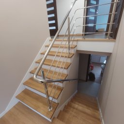 Metlux Rafał Żelazny - Schody z drewnianymi stopniami i nowoczesną, metalową poręczą. Widok z góry, ukazujący detale wykończenia i estetyczne połączenie materiałów.