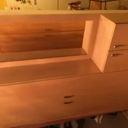 Jasnobrązowa szafa z lustrem i szufladami, nowoczesny design, metalowe uchwyty, widoczne detale wykończenia.