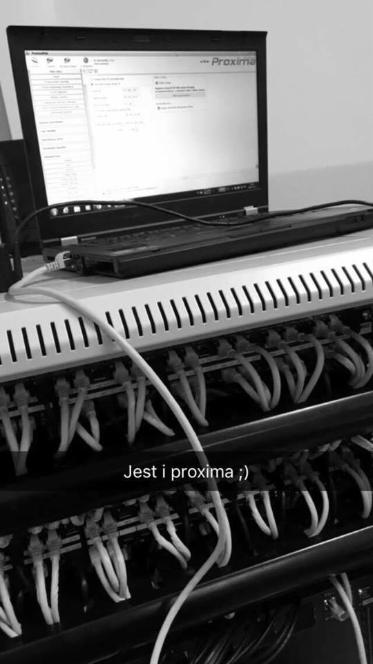 Czarno-białe zdjęcie serwera z podłączonymi kablami sieciowymi i laptopem z uruchomionym oprogramowaniem Proxima.