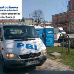 Biały samochód dostawczy z logo PBI Częstochowa na tle miasta, obok ustawione przenośne toalety w niebieskich obudowach.