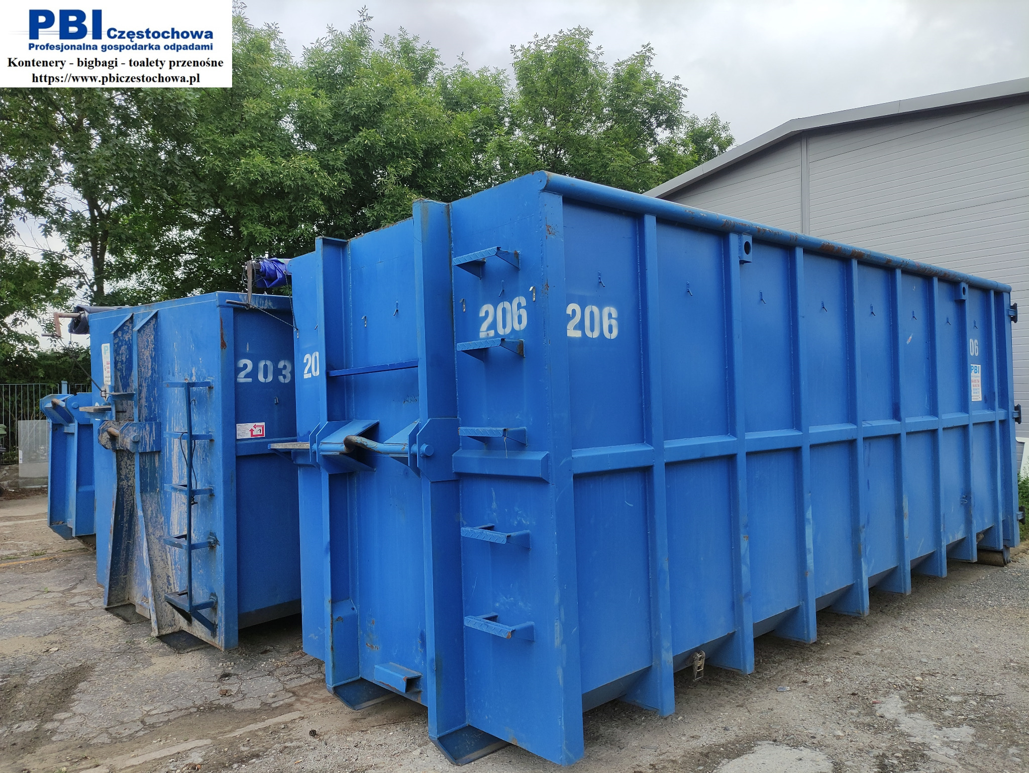 Dwa niebieskie, puste kontenery z numerami 203 i 206 stoją obok siebie na placu. Widoczne logo firmy PBI Częstochowa na jednym z kontenerów. W tle drzewa i budynek.