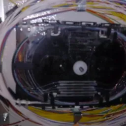 Zorganizowana wiązka kolorowych kabli światłowodowych wewnątrz panelu krosowniczego, widoczne złącza i oznaczenia kabli.