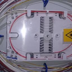 Tel-system Gabriela Łucek - Rozdzielnica światłowodowa z uporządkowanymi kablami, żółta naklejka ostrzegawcza o promieniowaniu laserowym.