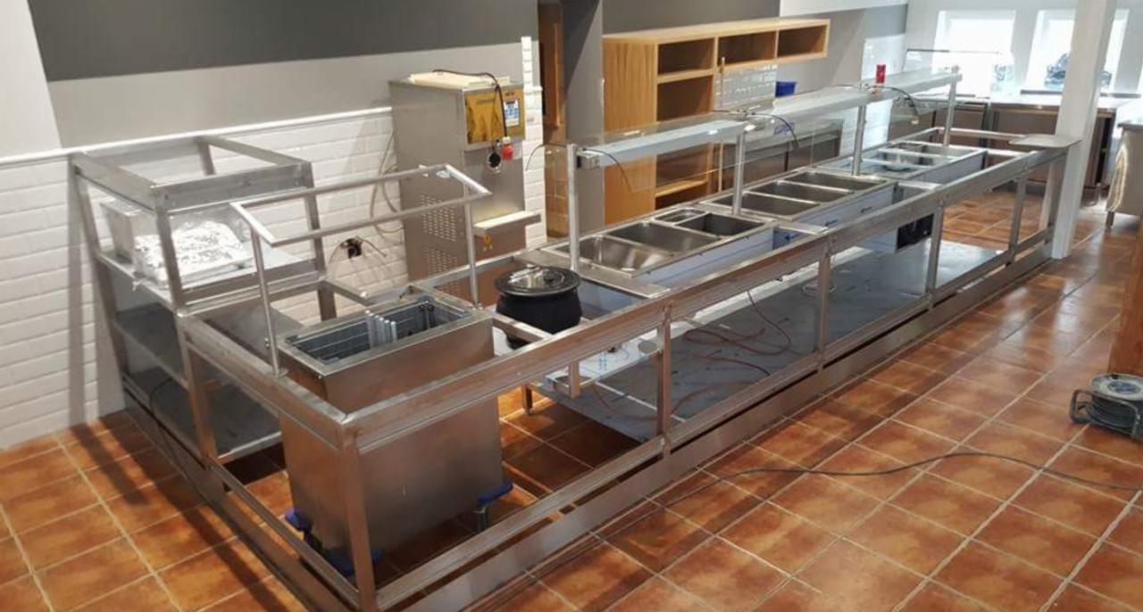 Konstrukcja ze stali nierdzewnej, prawdopodobnie element wyposażenia gastronomicznego, w trakcie montażu w lokalu, widoczne przewody i narzędzia.