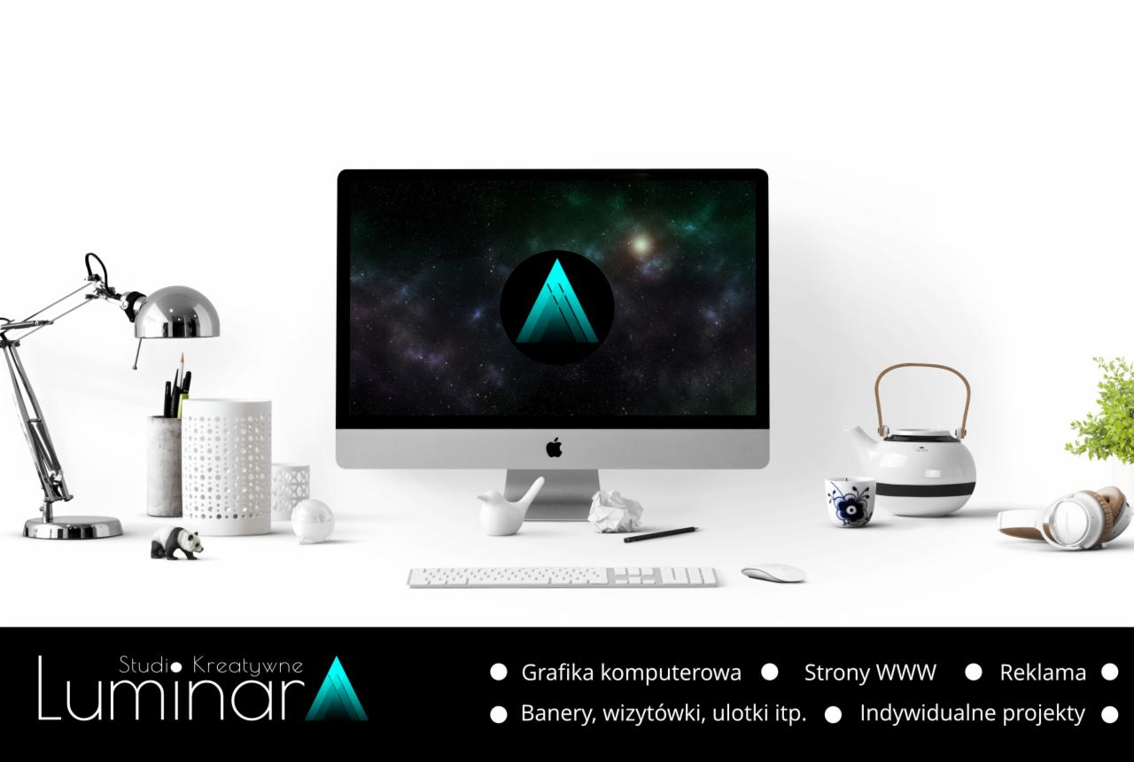 Monitor iMac wyświetlający logo studia kreatywnego na tle kosmicznej mgławicy, otoczony biurowymi akcesoriami i elementami dekoracyjnymi na białym biurku.